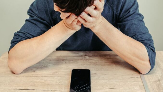 frustrated young man looking at his broken smartphone. Pojištění odpovědnosti zaměstnance